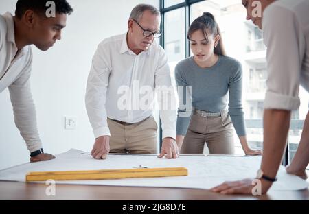 Planning ensures success. Cropped shot of four architects looking over blueprints in the office. Stock Photo