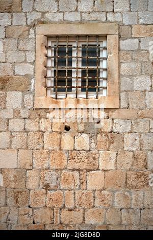 A vertical shot of building wall with window in front of window bars Stock Photo