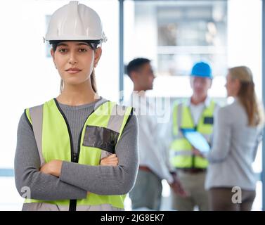 Confident in my construction skills. Cropped portrait of an attractive young female construction worker standing with her arms folded and her Stock Photo
