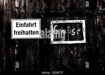 Two signs, keep driveway clear and handwritten sign 'Vegetables'. Stock Photo