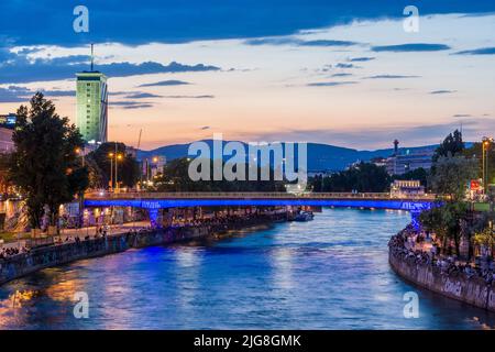 Vienna, river Donaukanal (Danube Canal), people sit on bank reinforcement, outdoor restaurants and bars, Ringturm high-rise in 01. district Old Town, Wien, Austria Stock Photo