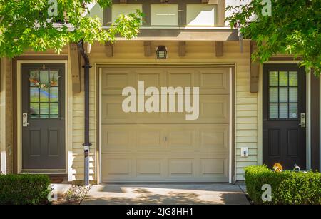 Garage doors at parking area for townhouses. Garage at residential area with green trees in summer day. Nobody, selective focus, street photo Stock Photo