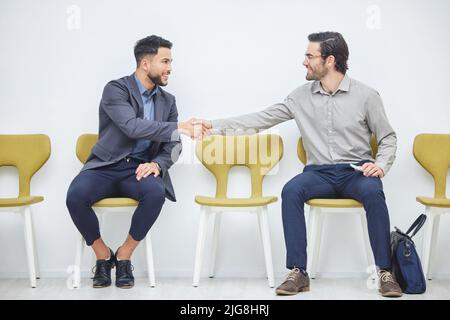 Making friends in the waiting room. Shot of two businessmen shaking hands while waiting to be interviewed. Stock Photo