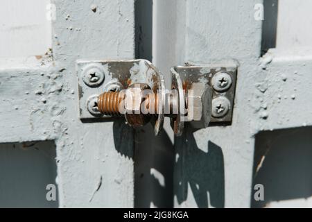 Old rusty bolt with screw nut used like a lock on the metal gate. Stock Photo