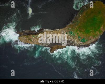 View from above. An amazingly shaped small island, overgrown with green grass, in the ocean. Abstraction. There are no people in the photo. Ecology, g Stock Photo