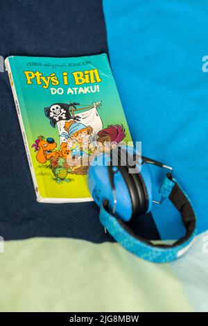 A vertical shot of a Polish comic book and a light blue ear protection placed on a bed Stock Photo