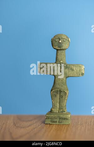A vertical shot of a Cyprus cross shaped fertility symbol standing on a wooden surface Stock Photo