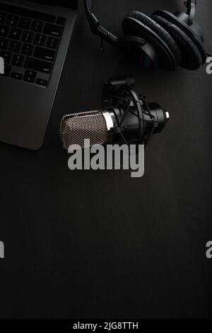 Laptop, studio microphone and studio headphones on a gray background. There are no people in the photo. There is free space to insert. Blogging, audio Stock Photo