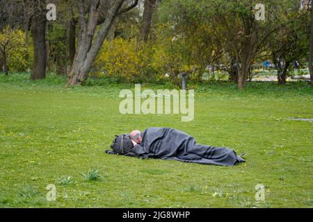 Germany, Bavaria, Munich, Old Botanical Garden, homeless man, sleeping on a meadow Stock Photo