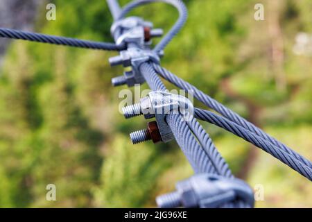 Reliable strong metal cable with connecting fastening with bolts and nuts of different sizes, outdoors Stock Photo