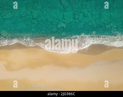 Green sea waves breaking on a golden sand shore. Top view directly above, natural background Stock Photo
