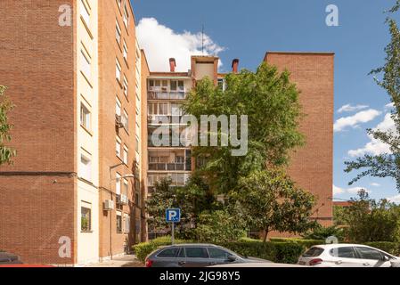 Facades of urban residential buildings made of brick clay with gardens and large trees Stock Photo