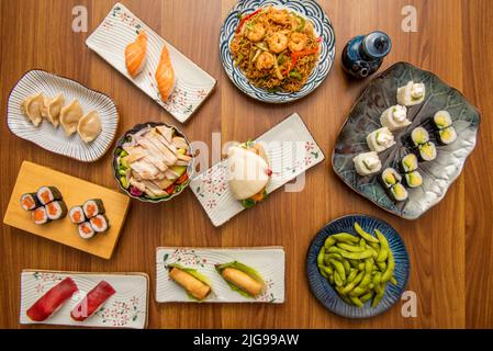 set of asian food dishes with sushi, avocado maki, shrimp noodles, soy sauce, spring rolls, bluefin tuna, edamame beans, gyozas, norwegian salmon and Stock Photo