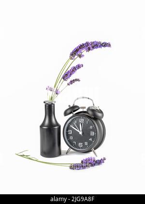 Lavender in dark vase with old alarm clock. Time passing concept. Stock Photo