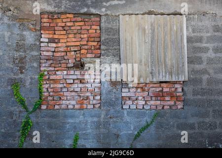 boarded up with red bricks windows of an old and broken building. Stock Photo