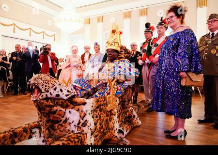 08 July 2022, Rhineland-Palatinate, Bad Dürkheim: Céphas Bansah, African king residing in Rhineland-Palatinate, is carried into the Kurhaus ballroom on a palanquin during the 'Golden Winemaker' award ceremony of the 'Derkemer Grawler' carnival society. On the right stands his wife Gabriele Bansah. Celebrities who have rendered outstanding services in socially important areas are honored. Bansah has lived in Ludwigshafen since 1970 and cares for more than 300,000 people from the Ewe tribe in Ghana from a distance. Photo: Uwe Anspach/dpa Stock Photo
