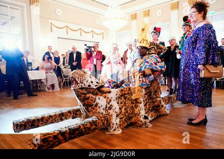08 July 2022, Rhineland-Palatinate, Bad Dürkheim: Céphas Bansah, African king residing in Rhineland-Palatinate, is carried into the Kurhaus ballroom on a palanquin during the 'Golden Winemaker' award ceremony of the 'Derkemer Grawler' carnival society. On the right stands his wife Gabriele Bansah. Celebrities who have rendered outstanding services in socially important areas are honored. Bansah has lived in Ludwigshafen since 1970 and cares for more than 300,000 people from the Ewe tribe in Ghana from a distance. Photo: Uwe Anspach/dpa Stock Photo