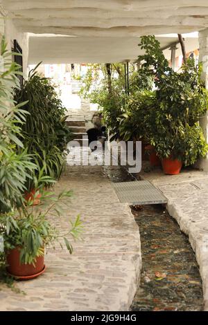 Gutter with water in a white street. To drain the rain from the mountains in winter Stock Photo