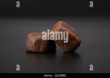 dark lumps of cannabis Moroccan hashish with high thc on a black background. Stock Photo