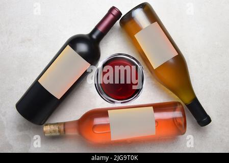 Cabernet, Rose, Chardonnay: Overhead view of a group of three different bottles with blank labels arranged in a triangle with a glass of wine in the m Stock Photo
