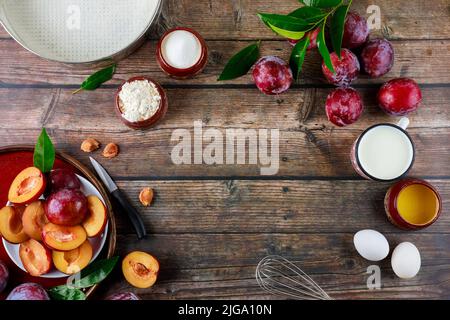 The ingredients of the baking process are eggs, whisk, plums, and a baking pan. Stock Photo