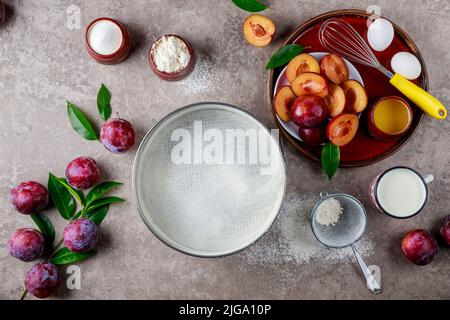 Using eggs, whisk, plum, and a baking pan are used in the baking process. Stock Photo