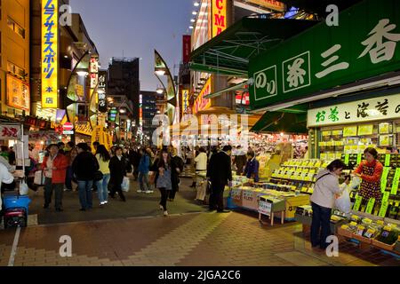 A bustling night scene of shoppers and brightly lit stores at dusk on Ameyoko Street Ueno, Tokyo, Japan Stock Photo