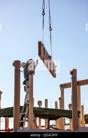 Construction worker guides beam at building site in Ikegami, Tokyo ...