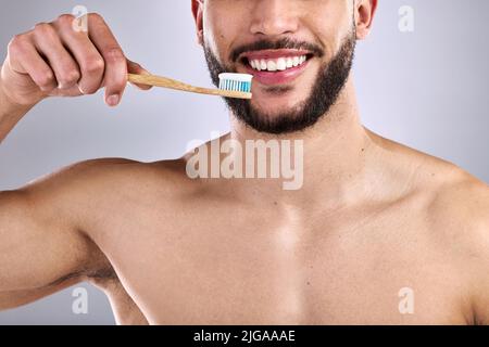 A wonderful smile is a few brushes away. a young man smiling while holding a toothbrush with toothpaste. Stock Photo