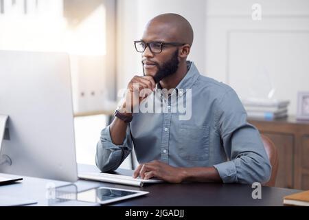 Ive got to put some thought into this. a young businessman using a computer in an office at work. Stock Photo