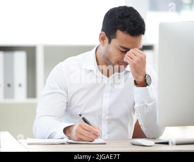 What was I meant to do today. a young businessman suffering from an headache at work. Stock Photo