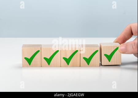 Checklist concept, check mark on wooden blocks with copy space. Hand holding wooden blocks with check marks. Checklist concept Check mark on wooden bl Stock Photo