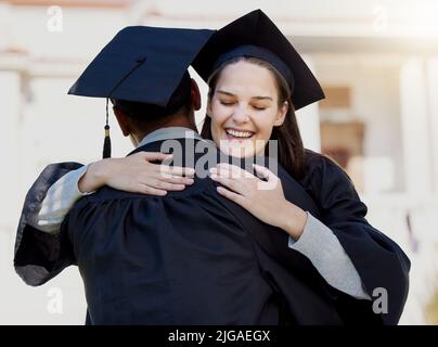 Thank you for pushing me to the end. Portrait of a young woman hugging her friend on graduation day. Stock Photo