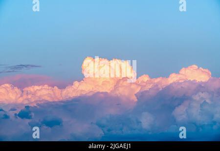 cumulus clouds at sunset. beautiful colored dramatic cumulus fluffy clouds on blue sky at sunset or sunrise Stock Photo