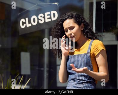 So were closing for good. a young female employee talking on a phone outside at work. Stock Photo