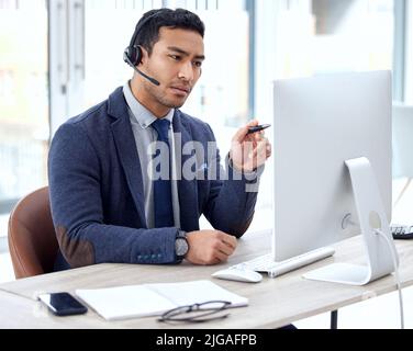 I see what the issue is. a customer service agent wearing a headset while sitting at his desk. Stock Photo
