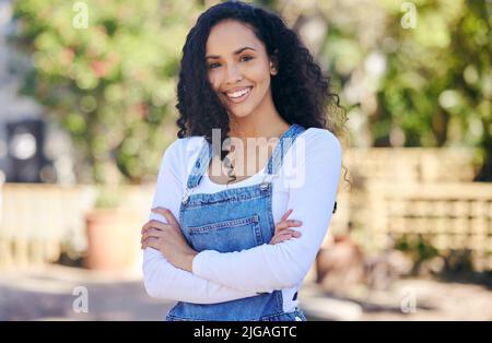 Surrounded by beautiful things. a beautiful young woman with folded arms standing outdoors. Stock Photo