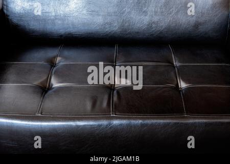 Seat of an old black leather sofa close up Stock Photo
