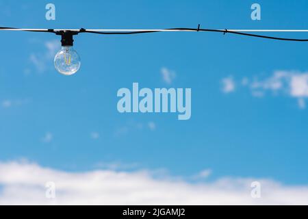 Vintage light bulb with blue sky and white clouds on background. Electricity concept. Earth hour. Energy consumption and environmental conservation Stock Photo