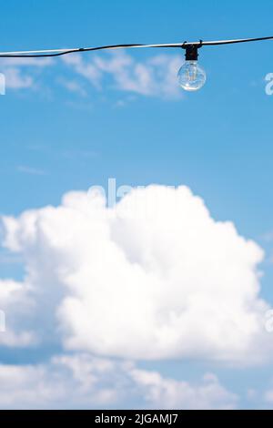 Vintage light bulb with blue sky and white clouds on background. Electricity concept. Earth hour. Energy consumption and environmental conservation Stock Photo