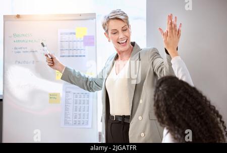 Chasing after success with every plan they make. a senior businesswoman giving her colleague a high five during a meeting in an office. Stock Photo