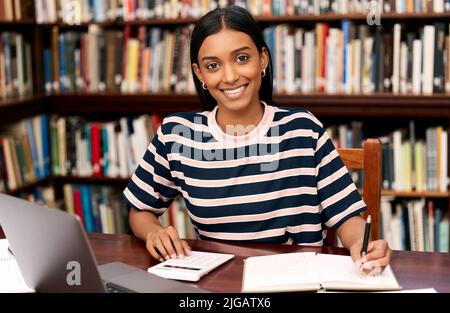 I was made for the student life. a young female student studying in a library at college. Stock Photo