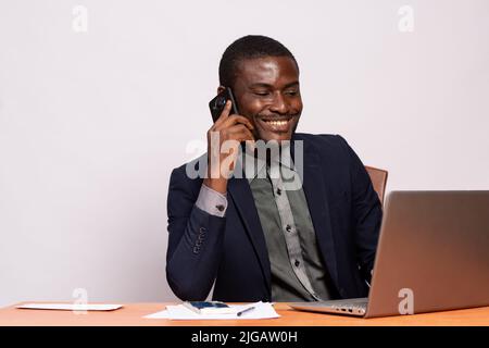 black businessman making a call while using his laptop Stock Photo
