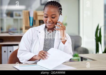 Technology has greatly helped modern medicine. a young female doctor making a phone call using her smartphone. Stock Photo