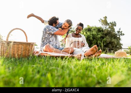 Happy multiracial family having fun together while doing picnic in the park Stock Photo