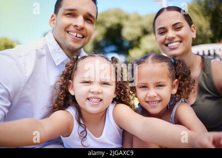 The moments in between make the best memories. Portrait of a happy young family taking selfies during a fun day out at the park. Stock Photo