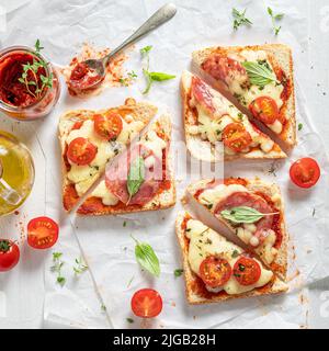 Fresh and tasty toasts with salami, tomato and cheese. Crispy toasts with salami and cheese. Stock Photo