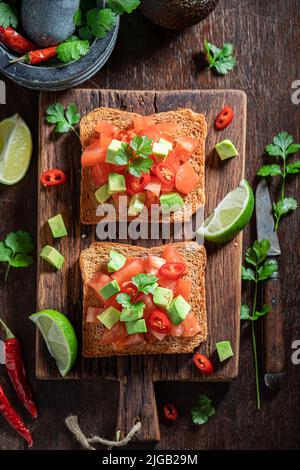 Crunchy and delicious toasts made of tomatoes, avocado and chilli pepper. Crunchy toasts as a quick snack. Stock Photo