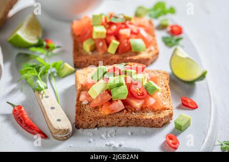 Tasty and fresh toasts with tomatoes, lime and coriander. Crunchy toasts as a quick snack. Stock Photo