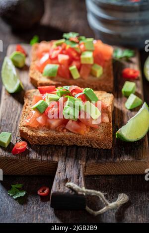 Tasty and fresh toasts with avocado, tomatoes and coriander. Crunchy toasts as a quick snack. Stock Photo